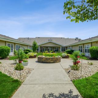 A courtyard with green landscaping and a central pathway leading to a building.