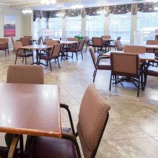 An empty dining room with neatly arranged tables and chairs in a bright, window-lit space.