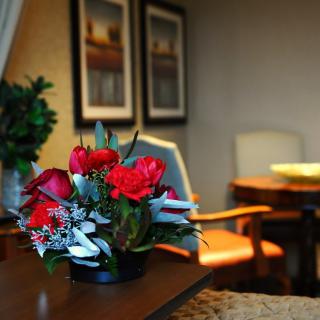 A cozy room with a vibrant red flower arrangement on a wooden table.