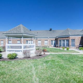 A sunny day view of a brick building with a gazebo and well-maintained lawn.