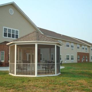 A residential building with a screened gazebo on a grassy lawn.