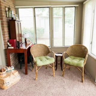 A cozy sunroom with wicker chairs and a small desk by the window.