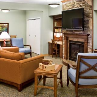 A cozy living room with a fireplace and modern decor, featuring comfortable seating and a mounted television.