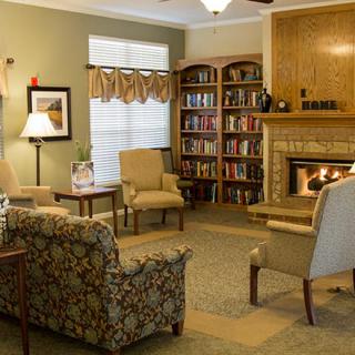 A cozy living room with a fireplace, bookshelves, and comfortable seating.