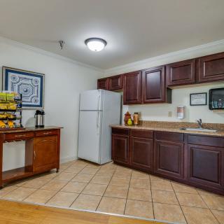 A kitchen with dark wooden cabinets, a refrigerator, and a tiled floor.