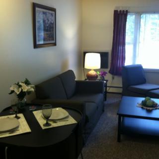A cozy living room with a sofa, coffee table, and dining setup.