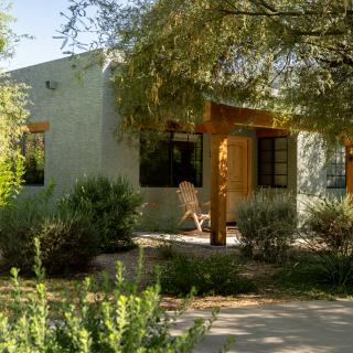 A cozy house surrounded by lush greenery and bathed in sunlight.
