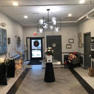 A modern lobby with stylish decor, featuring a central floral arrangement, artwork on the walls, and a comfortable seating area.