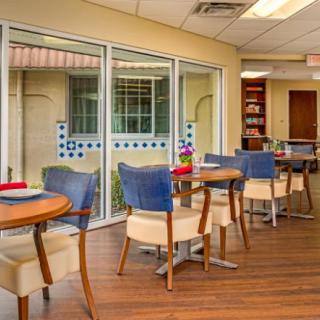 A modern dining area with tables and chairs adjacent to large windows.