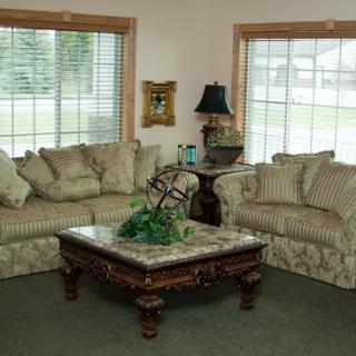 A cozy living room setup featuring a striped sofa, a decorative coffee table, and natural light streaming in through the windows.