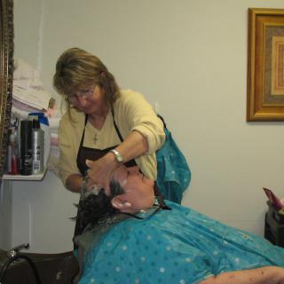 A hairstylist washes a client's hair in a salon setting.