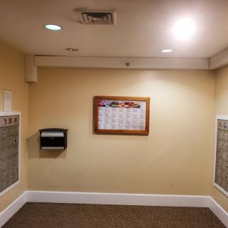 An interior view of a mailroom featuring mailboxes on the walls and a notice board in the center.
