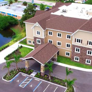 Aerial view of a multi-story building with a parking lot and surrounding landscape.