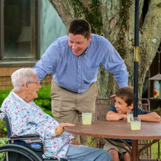 A warm family moment as a man engages in conversation with an elderly woman and a young boy in a cozy outdoor setting.