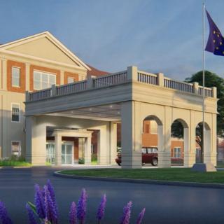 A hospital building with an entrance, surrounded by landscaping and a flagpole.