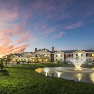 A beautiful building with a fountain in front, set against a stunning sunset backdrop.