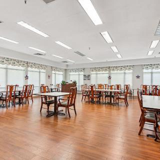 A spacious dining area featuring wooden tables and chairs with ample natural light.