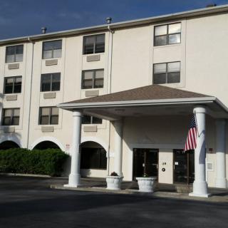 Exterior view of a hotel with a covered entrance and American flag.