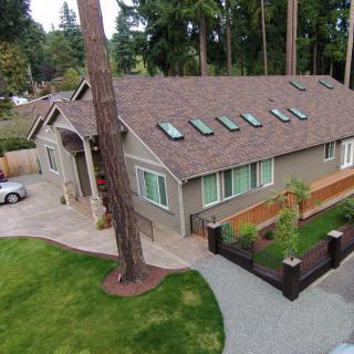 Aerial view of a suburban house with a well-maintained yard and surrounding trees.