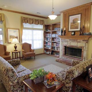 A cozy living room with a fireplace, comfortable seating, and a bookshelf.