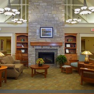 A cozy living room with a stone fireplace, comfortable seating, and wooden bookshelves.