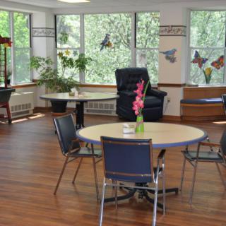 A cozy room with tables and chairs, decorated with plants and colorful wall art.
