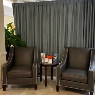 A cozy waiting area with two armchairs and a small table in front of curtains.