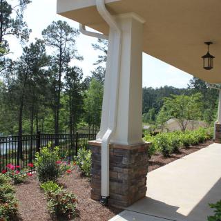 A well-landscaped porch area with columns and a garden path overlooking lush greenery.