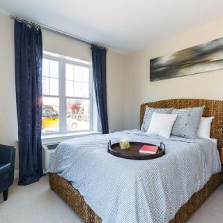 A cozy, modern bedroom with a wicker bedframe, blue curtains, and a tray on the neatly made bed.