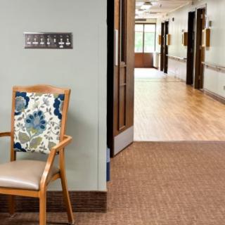 A hallway with a wooden chair featuring a floral cushion and visible signage on the wall.