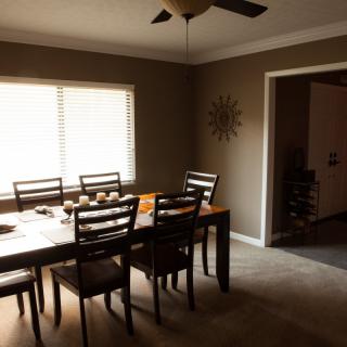 A cozy dining room with a wooden table, chairs, and natural light filtering through the window.