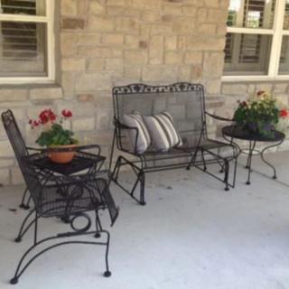 A cozy outdoor patio setup with iron furniture and potted plants against a brick wall.