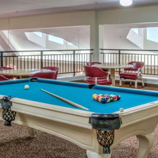 A stylish game room featuring a blue-felt pool table with cues and balls ready for play, surrounded by comfortable seating.