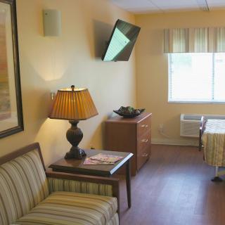 A cozy hotel room with a television, lamp, and comfortable furnishings.