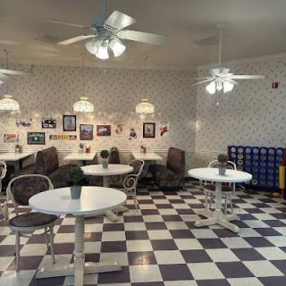 A cozy caf interior featuring a checkered floor, round tables, and comfortable seating.
