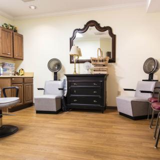 A cozy salon interior featuring chairs, mirrors, and hairdryers with a wooden floor.