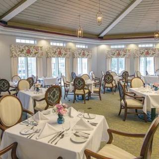 An elegant dining room with neatly arranged tables and chairs, featuring classic decor and bright lighting.