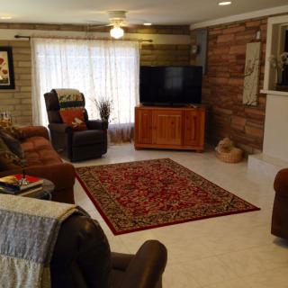A cozy living room with comfortable seating, a television, and a patterned rug.