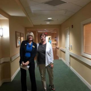 Two people standing in a well-lit hallway.