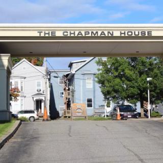 Entrance to The Chapman House with surrounding buildings and parked cars.