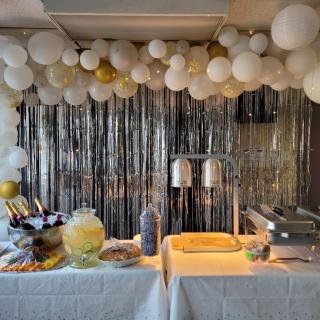 A festive buffet setup with balloon decorations and a variety of food items.