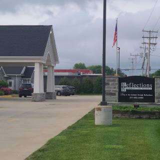 A view of a building with a sign indicating the establishment, along with a flag and surrounding greenery.