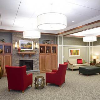 A cozy lobby area with red chairs, a fireplace, and elegant decor.