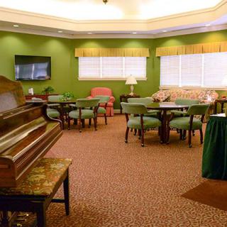 A cozy room with a piano, multiple seating areas, and a television.