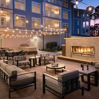 A cozy outdoor patio with modern furniture, a fireplace, and string lights creates an inviting evening atmosphere.