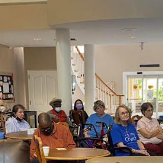 A diverse group of individuals seated together in a communal space, likely engaged in a discussion or activity.