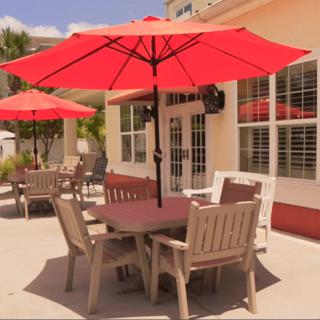 A sunny patio with tables and red umbrellas.
