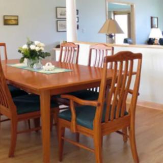 A cozy dining room with a wooden table and chairs, featuring a floral centerpiece.