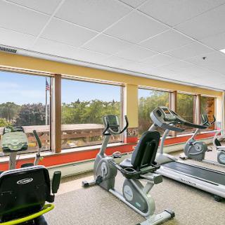 A modern fitness center with various exercise equipment and large windows allowing natural light.