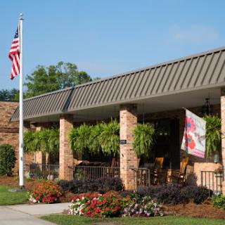 A welcoming building with outdoor seating, adorned with vibrant flowers and an American flag.